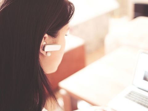 Frau mit kabellosen Headset im Ohr