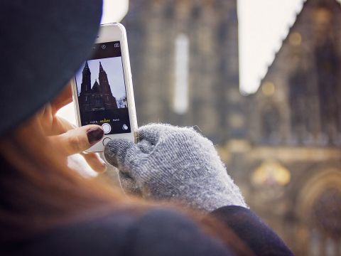 Frau bedient ihr Smartphone mit Handschuhen an den Händen