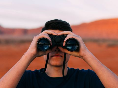 Mann mit Fernglas vor den Augen