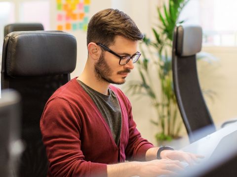 Mann arbeitet konzentriert an seinem Computer.