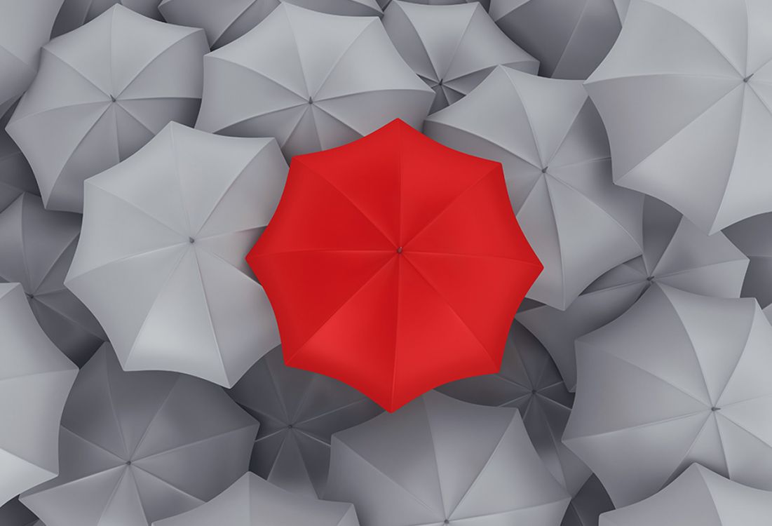 Roter Regenschirm umgeben von grauen Regenschirmen