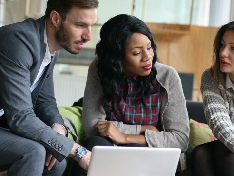 Team sitzt vor Laptop und beratschlagt sich